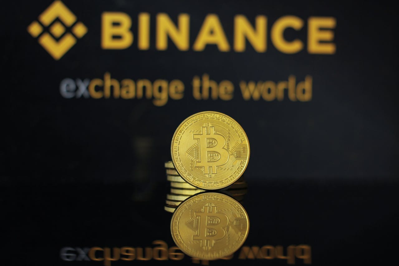 Close-up of a Bitcoin coin with Binance logo and text reflecting in dark surface.